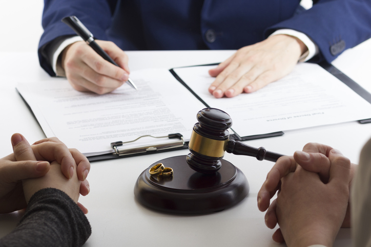 Hands of wife, husband signing decree of divorce, dissolution, canceling marriage, legal separation documents, filing divorce papers or premarital agreement prepared by lawyer. Wedding ring.